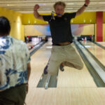 David springt in die Luft vor einer Bowling-Bahn.